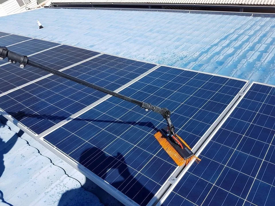 Cleaning solar panels with a brush on a rooftop for maintenance.