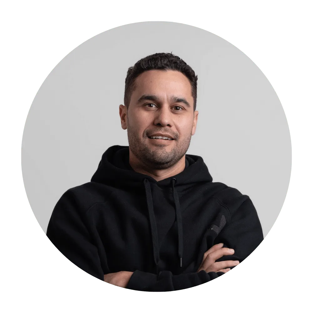 Man in black hoodie with arms crossed, smiling confidently